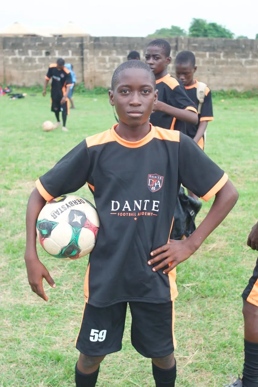 A Dante player standing with a football in official academy kit