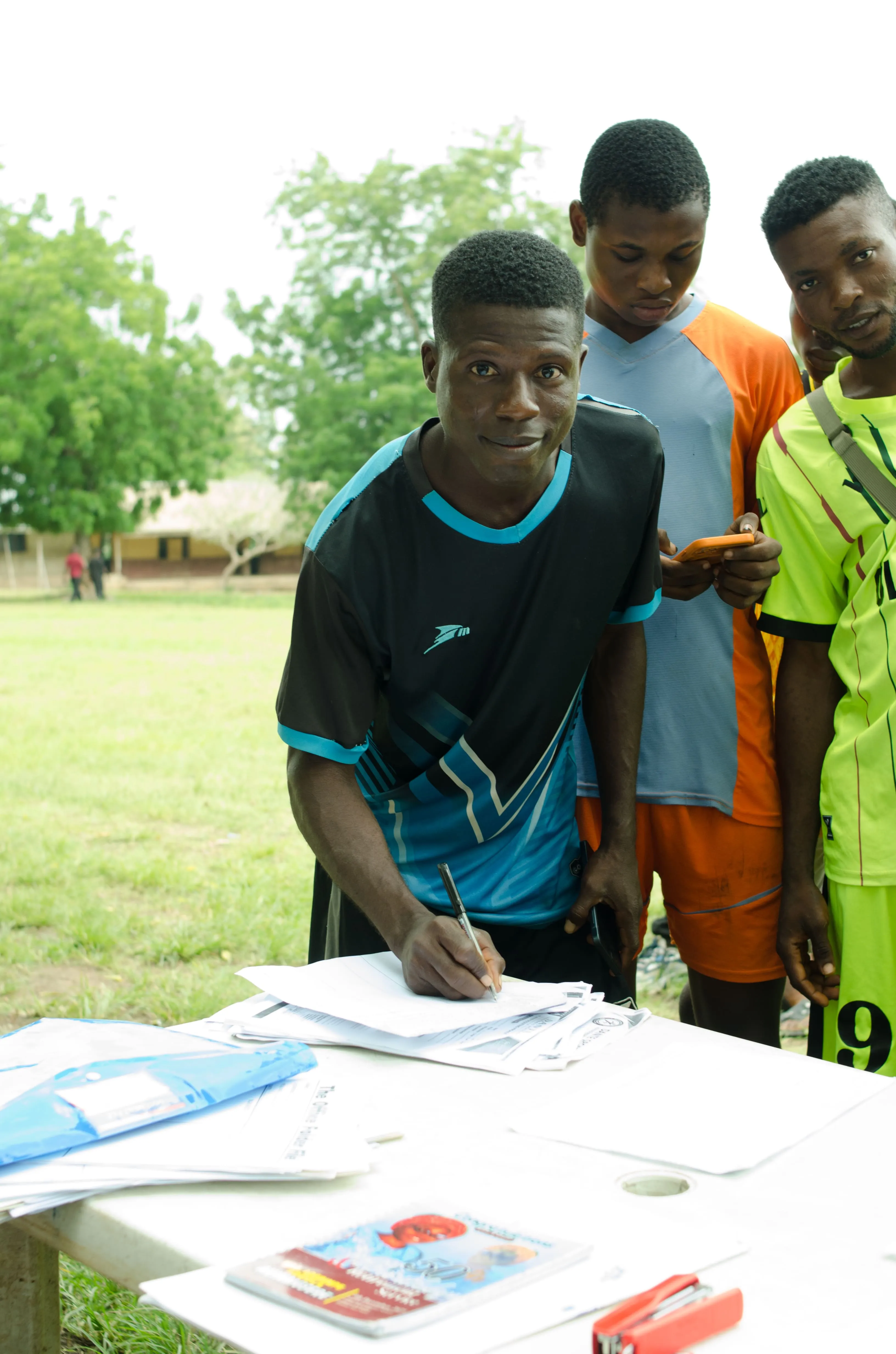 A player completing event documentation with teammates nearby